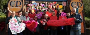 Group of people posing in front of C&P Coffee Shop holding heart shaped valentines in support of its preservation.