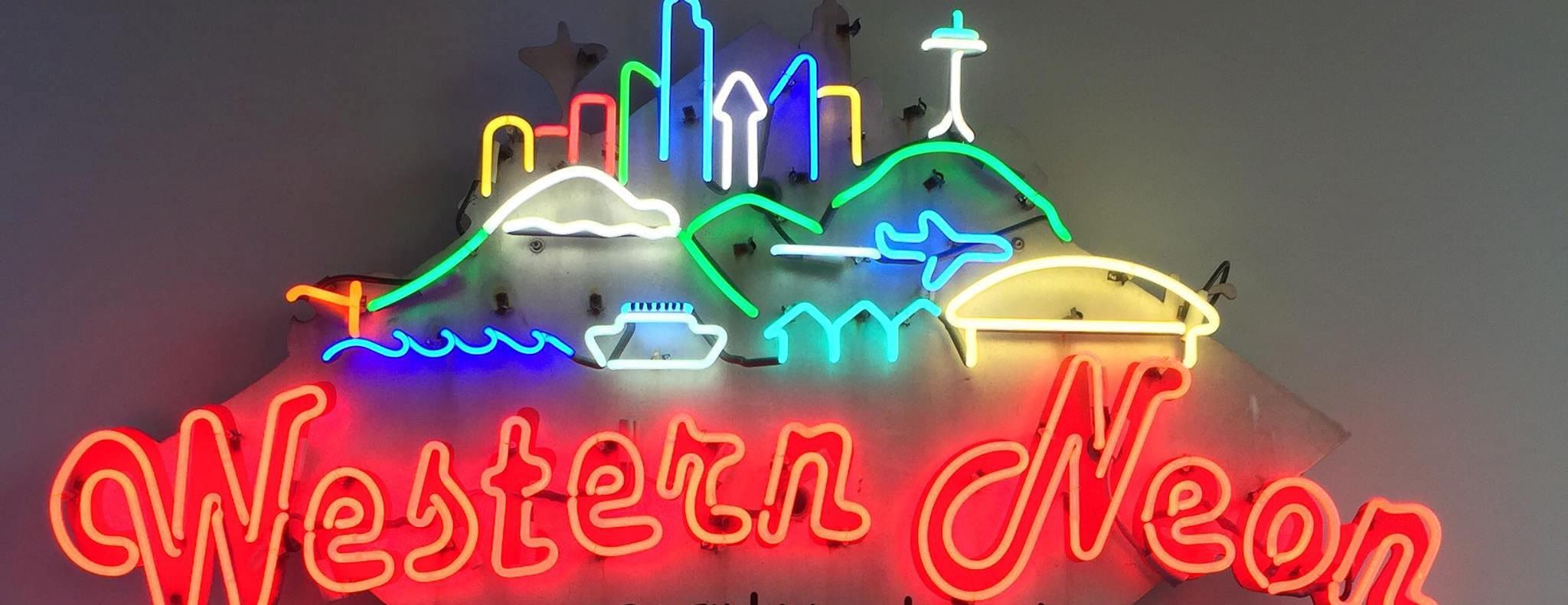 Western Neon's own neon sign, which depicts Mount Rainier, the Seattle Skyline, a jet, CenturyLink Field, and a boat on the water.