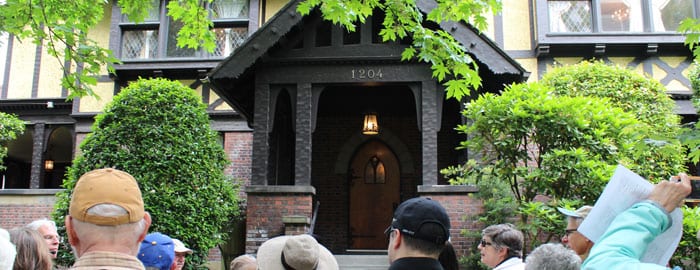 A group of people stand before the entrance to the Stimson-Green Mansion, which is flanked by bushes.