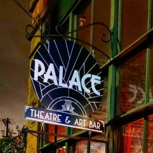 A black, circular sign with "PALACE THEATRE & ART BAR" in white lettering